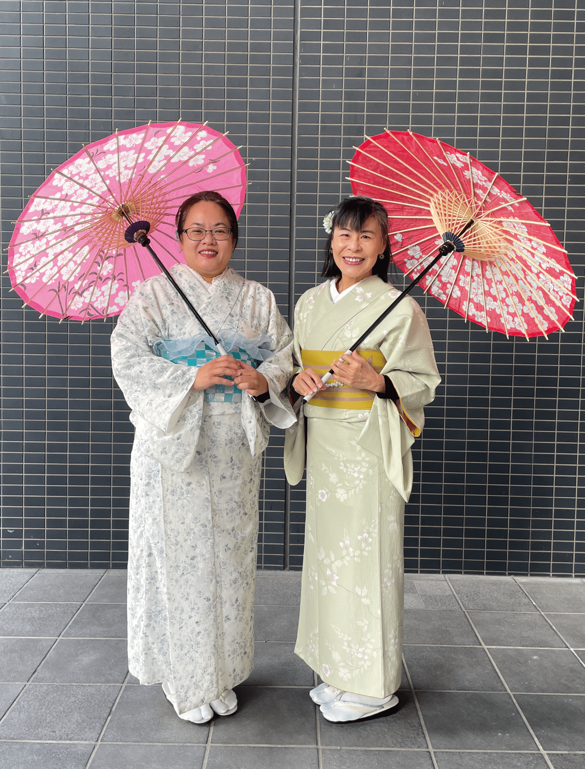 女性二人が着物に身を飾り和傘をもって京都で記念撮影